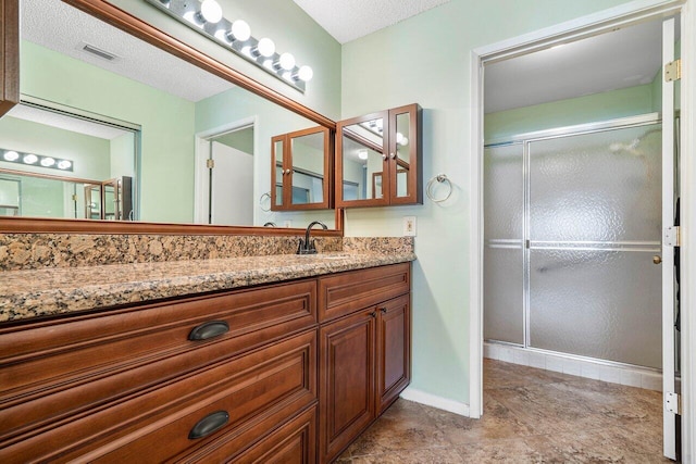 bathroom with vanity, a textured ceiling, and walk in shower