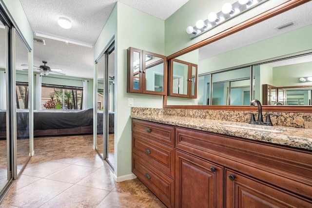 bathroom featuring ceiling fan, tile patterned flooring, vanity, and a textured ceiling