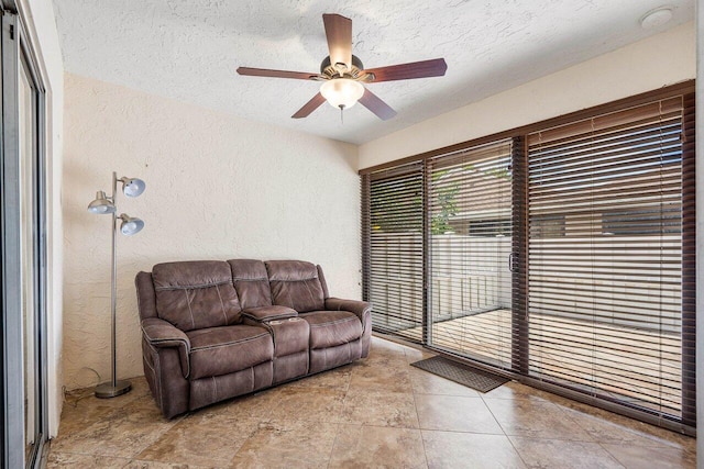 living room featuring ceiling fan and a textured ceiling