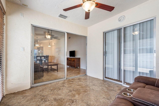 living room with ceiling fan and a textured ceiling