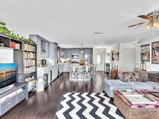 living room featuring ceiling fan and dark wood-type flooring