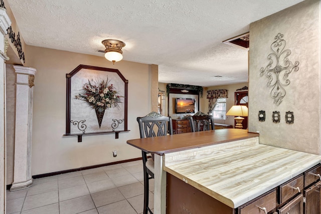 kitchen featuring a textured ceiling, kitchen peninsula, and light tile patterned floors