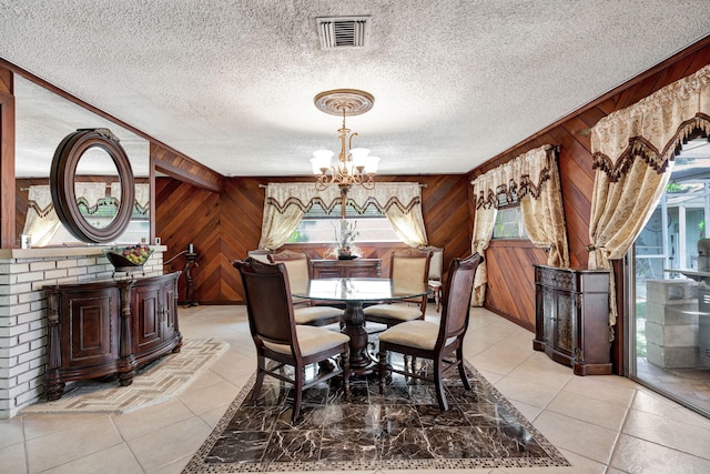 dining room with a textured ceiling, wooden walls, and light tile patterned floors