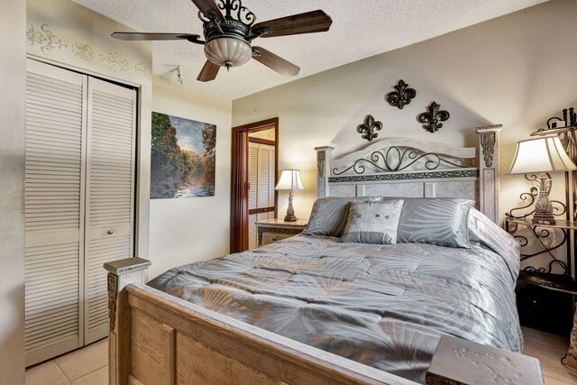 bedroom with light tile patterned flooring, a textured ceiling, ceiling fan, and a closet