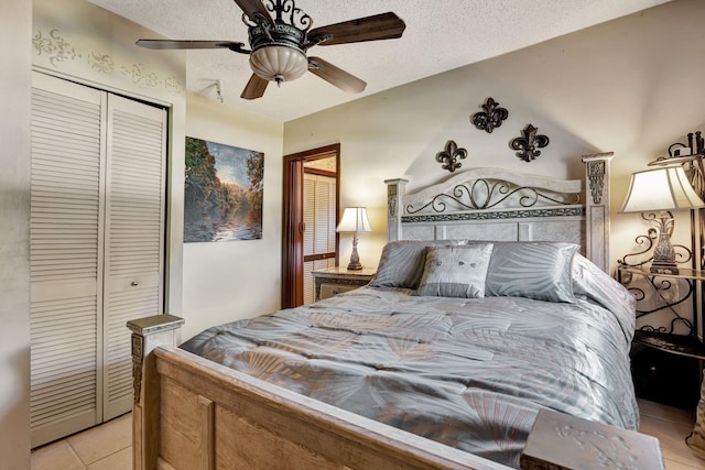 bedroom featuring ceiling fan, a closet, a textured ceiling, and light tile patterned floors