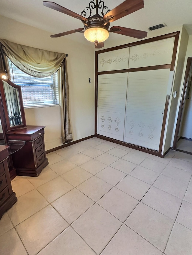 unfurnished bedroom with light tile patterned flooring, a closet, and ceiling fan