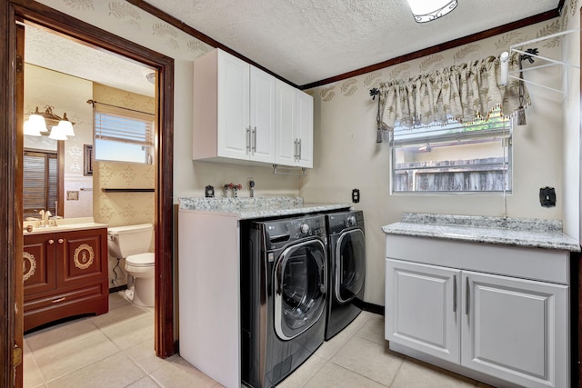 laundry room featuring separate washer and dryer, cabinets, a textured ceiling, and light tile patterned floors