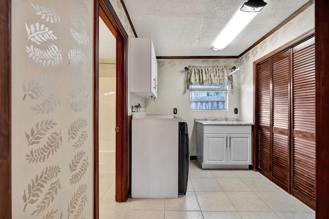 washroom with ornamental molding, cabinets, a textured ceiling, and light tile patterned floors