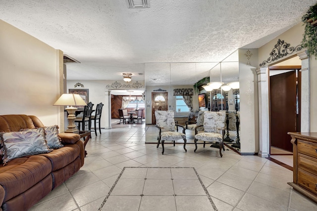 living room featuring ornate columns, light tile patterned flooring, and a textured ceiling