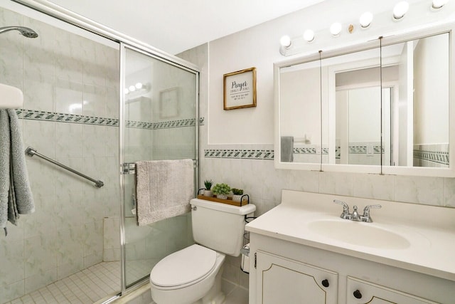 bathroom featuring vanity, toilet, an enclosed shower, and tile walls