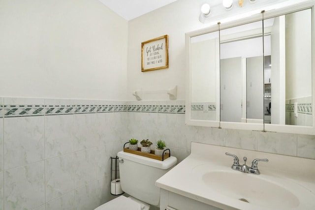 bathroom featuring vanity, toilet, and tile walls