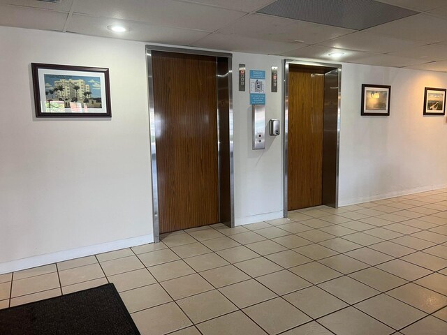 unfurnished room featuring light tile patterned floors and elevator