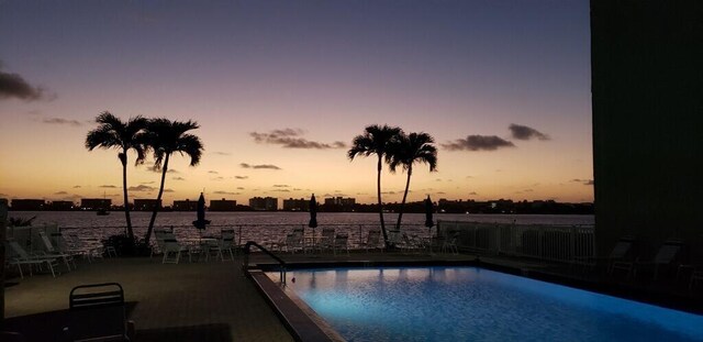 pool at dusk featuring a patio area and a water view