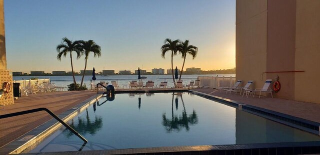 pool at dusk with a water view and a patio area