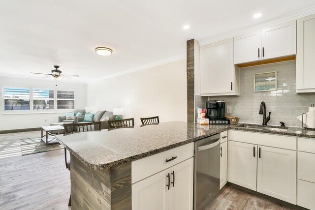 kitchen with dishwasher, light hardwood / wood-style floors, dark stone countertops, and sink