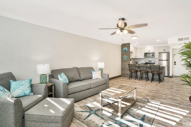 living room featuring ceiling fan and light hardwood / wood-style flooring