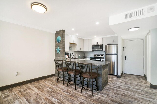 kitchen featuring sink, stainless steel appliances, a kitchen breakfast bar, kitchen peninsula, and white cabinets