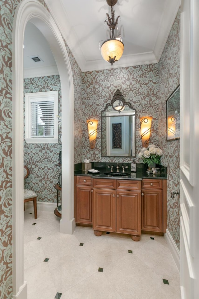 bathroom with ornamental molding, vanity, baseboards, and wallpapered walls