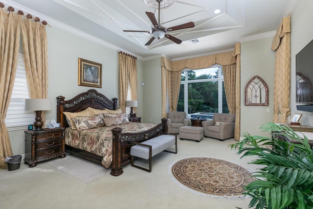 bedroom with a tray ceiling, light colored carpet, visible vents, ornamental molding, and a ceiling fan