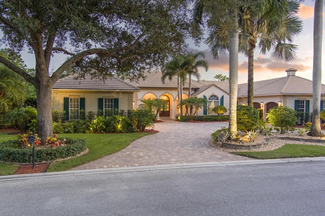 view of front of home featuring decorative driveway, a lawn, and stucco siding