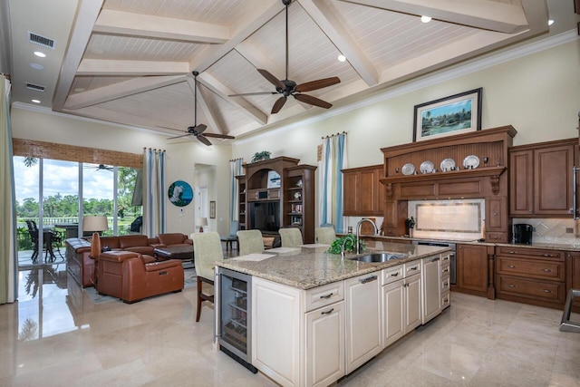 kitchen featuring a center island with sink, white cabinets, wine cooler, open floor plan, and a sink