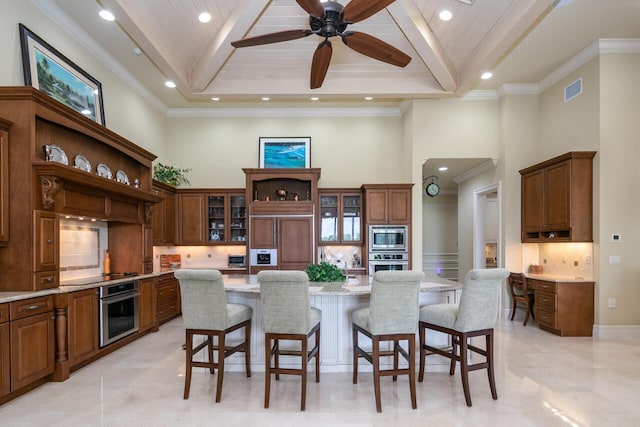 7380 SE Medalist Pl, Hobe Sound, FL 33455 - kitchen with high vaulted ceiling, open shelves, a breakfast bar, a spacious island, and appliances with stainless steel finishes