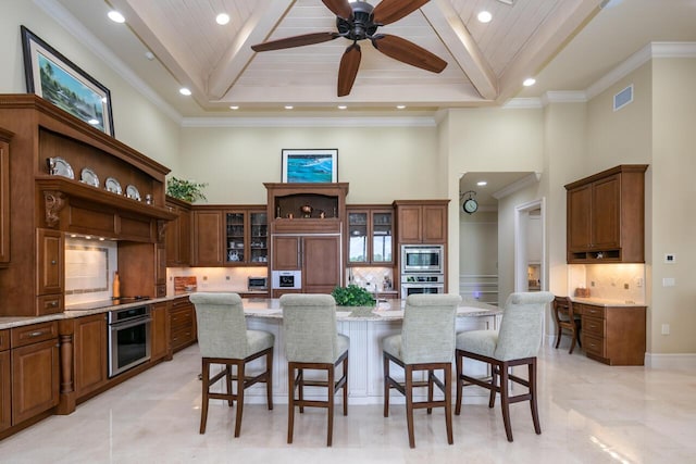 kitchen with built in appliances, a breakfast bar, a center island, light stone countertops, and glass insert cabinets