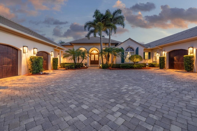 mediterranean / spanish home featuring decorative driveway, an attached garage, and stucco siding