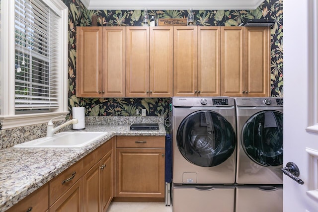 clothes washing area with a sink, wallpapered walls, cabinet space, and washing machine and clothes dryer