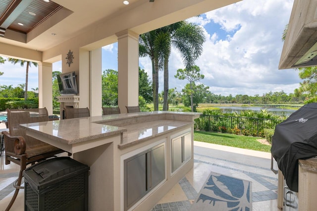 view of patio featuring an outdoor kitchen, grilling area, a water view, and outdoor wet bar