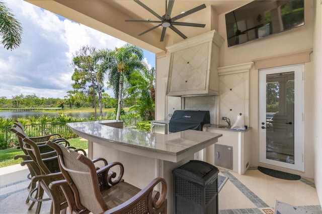 view of patio / terrace with outdoor wet bar, area for grilling, a water view, a grill, and a ceiling fan