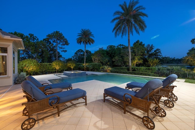 view of pool with a patio area, fence, and a pool with connected hot tub