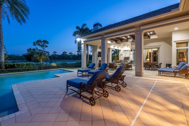 pool at dusk with a fenced in pool and a patio area