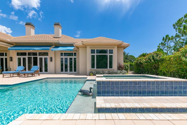 pool with french doors, a patio, and an in ground hot tub