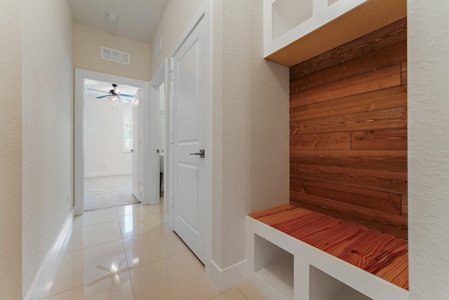 mudroom featuring light tile patterned floors, ceiling fan, and wood walls