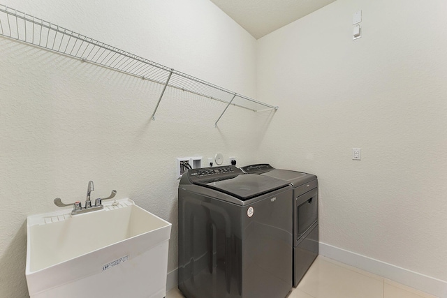 laundry area featuring washer and clothes dryer, sink, and light tile patterned floors