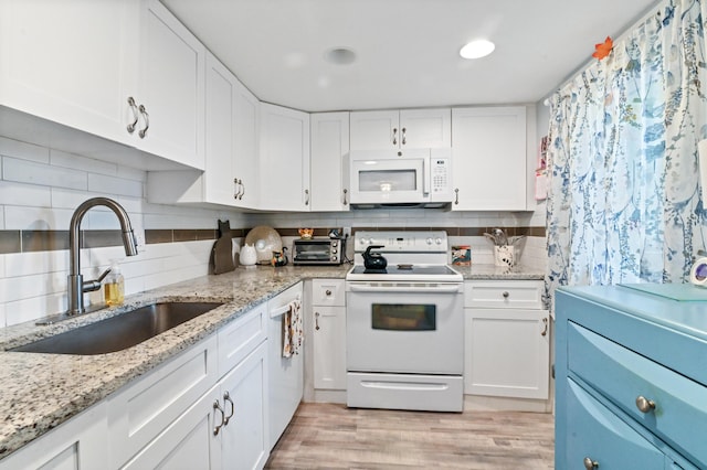 kitchen featuring white appliances, white cabinets, sink, decorative backsplash, and light stone countertops