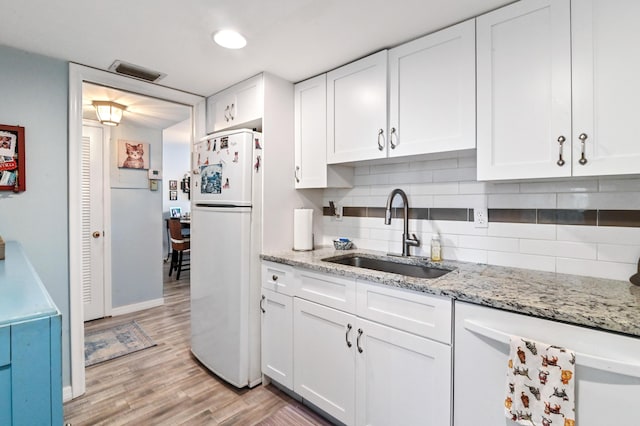 kitchen with light stone countertops, sink, backsplash, white appliances, and white cabinets