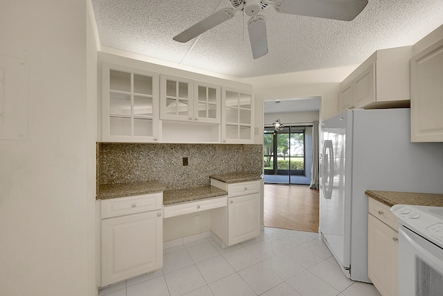 kitchen with backsplash, dark stone counters, ceiling fan, light tile patterned floors, and white cabinetry