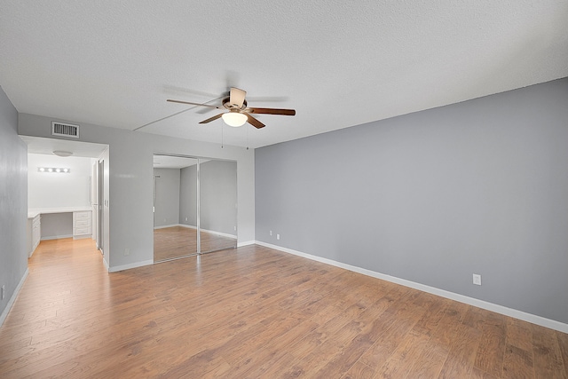 unfurnished bedroom featuring ceiling fan, light hardwood / wood-style floors, a textured ceiling, and a closet