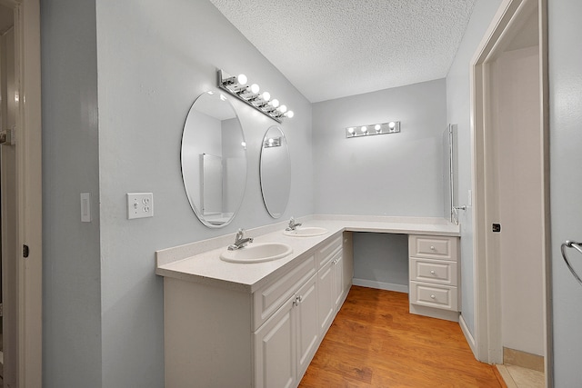 bathroom with hardwood / wood-style floors, vanity, and a textured ceiling