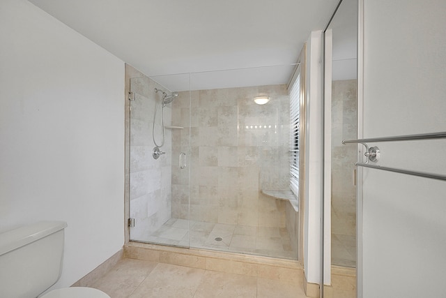 bathroom featuring tile patterned flooring, toilet, and a shower with shower door