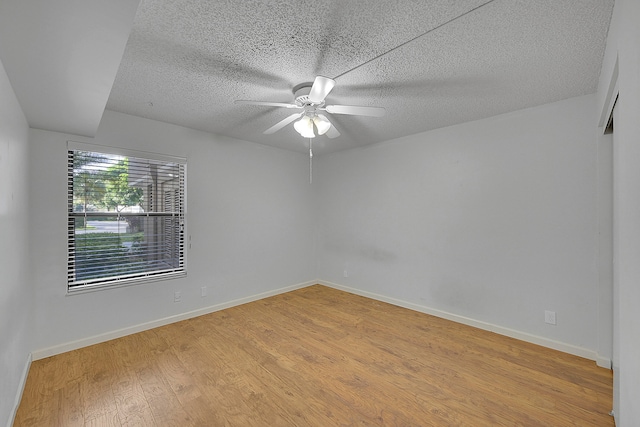 unfurnished room with ceiling fan, light wood-type flooring, and a textured ceiling