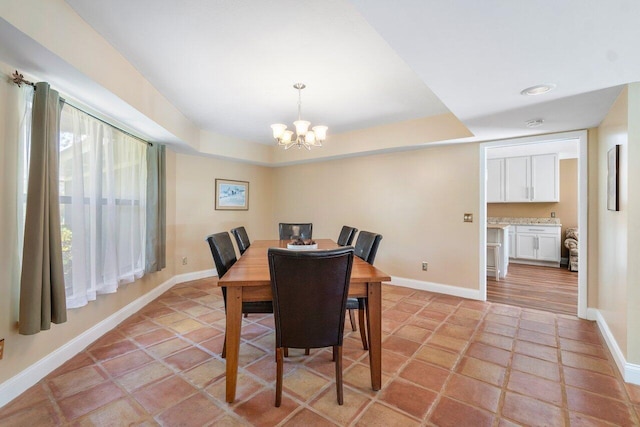 dining room featuring a notable chandelier, light tile patterned flooring, and a tray ceiling