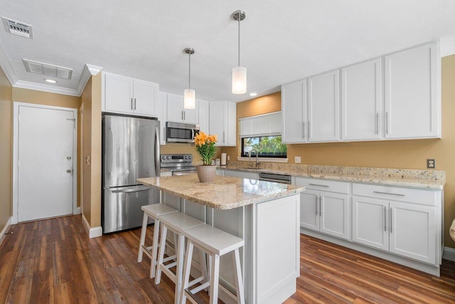 kitchen featuring stainless steel appliances, decorative light fixtures, crown molding, dark hardwood / wood-style floors, and a center island