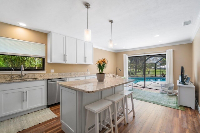 kitchen with decorative light fixtures, sink, white cabinets, a center island, and stainless steel dishwasher