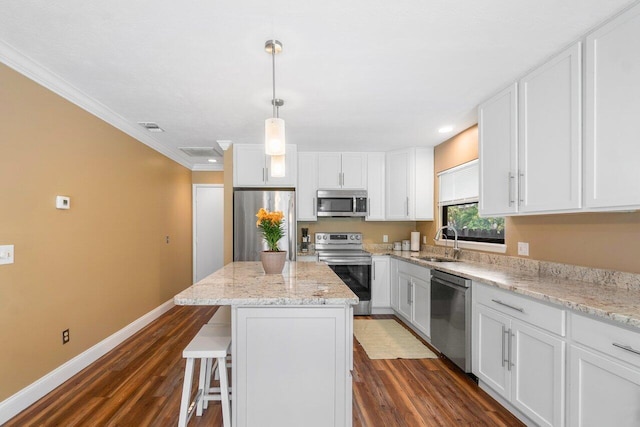 kitchen with dark hardwood / wood-style flooring, ornamental molding, sink, a center island, and appliances with stainless steel finishes