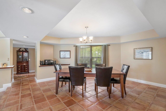 tiled dining space with an inviting chandelier and a tray ceiling