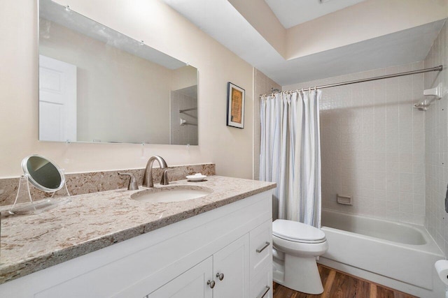 full bathroom featuring hardwood / wood-style flooring, shower / bathtub combination with curtain, vanity, and toilet