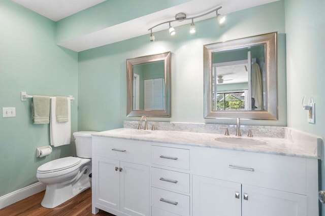 bathroom with hardwood / wood-style floors, toilet, dual bowl vanity, and track lighting